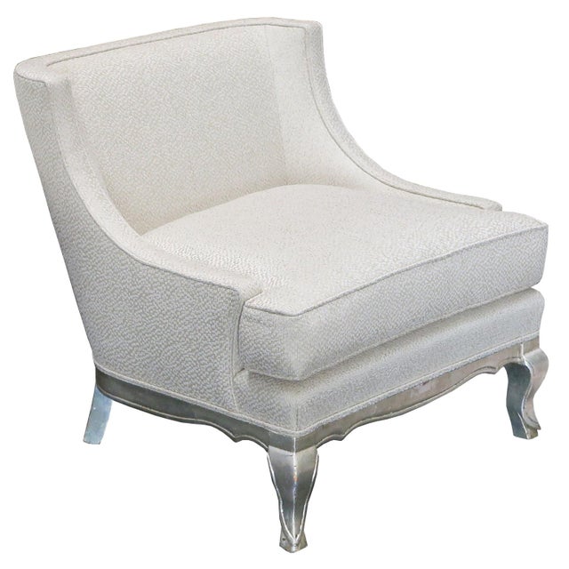 Elegant pair of French salon or lounge chairs with carved legs and base in distressed silver leaf. Curved arms with tight...