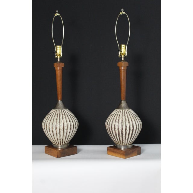 A pair of sculptural pair inspired by organic elegance of mid century design. Thesr ceramic and walnut lamps bring warmth...
