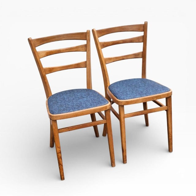 A charming pair of Eastern European beech dining chairs, showcasing classic ladder-back silhouettes paired with softly...