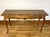 A French Provincial style console sofa table in a warm honey-brown tone with a shaped serpentine top edge, two drawers,...