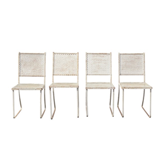 A set of four perfectly patina'ed mid century modern perforated metal patio chairs, French style. The chairs are a mix of...
