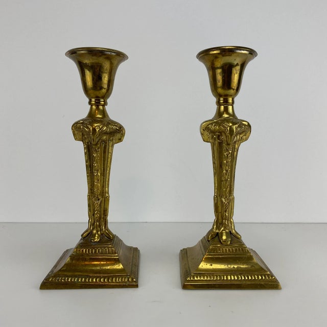 Pair of brass colored metal candlestick featuring ram head at the top of the stem.
