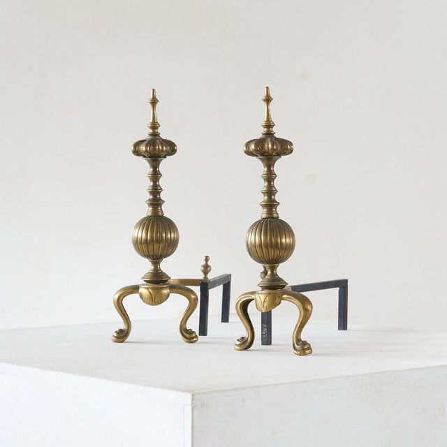 Pair of Large Neoclassical Andirons in Patinated Brass. Europe, mid to late 19th century. A large and imposing pair of...
