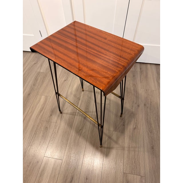 Made in Italy, 1960s. This side table features a varnished iron-and-brass frame, a multi-layered ebonized beech top, and a...