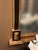 An elegant statement mirror featuring an intricate gold-tone frame with contrasting black accents. The sculptural...