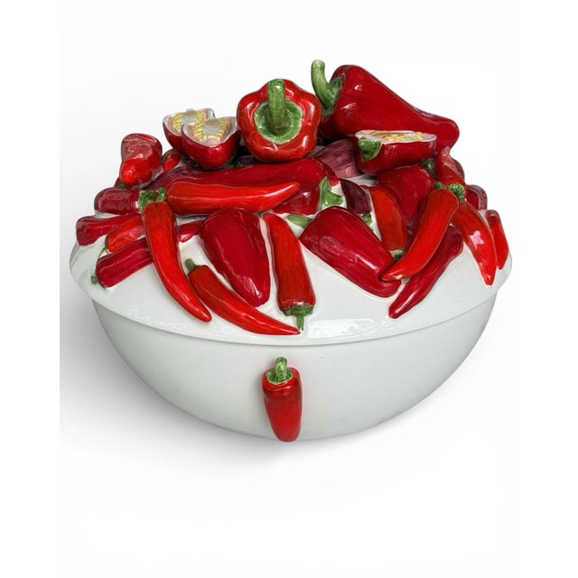 A striking Italian ceramic chili pepper tureen featuring a sculptural lid bursting with glossy red peppers and usable as...