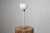 Swedish modern table light from the 1930s to 1940s. The light is likely by Böhlmarks. It has a foot in brass and a white...