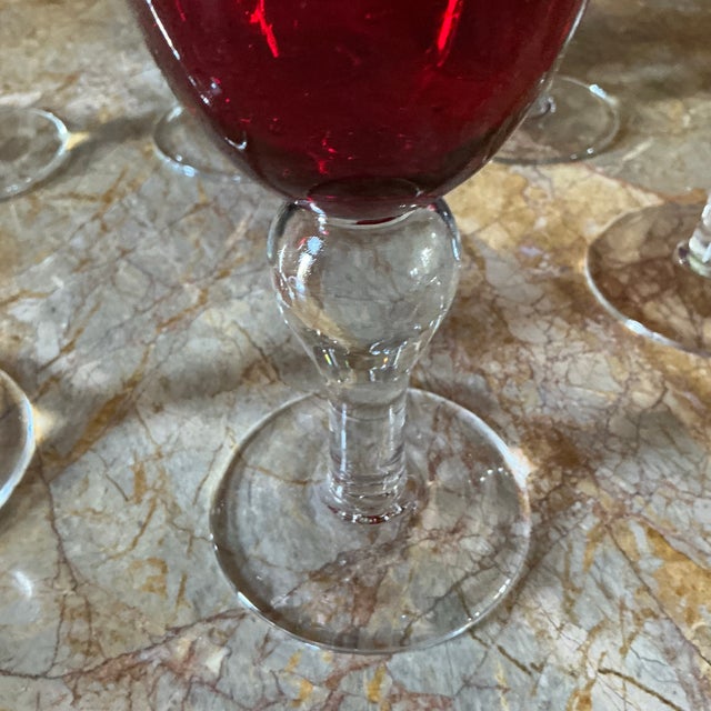 A striking set of six vintage ruby‑red glass goblets featuring clear, faceted stems and beautifully saturated red bowls....