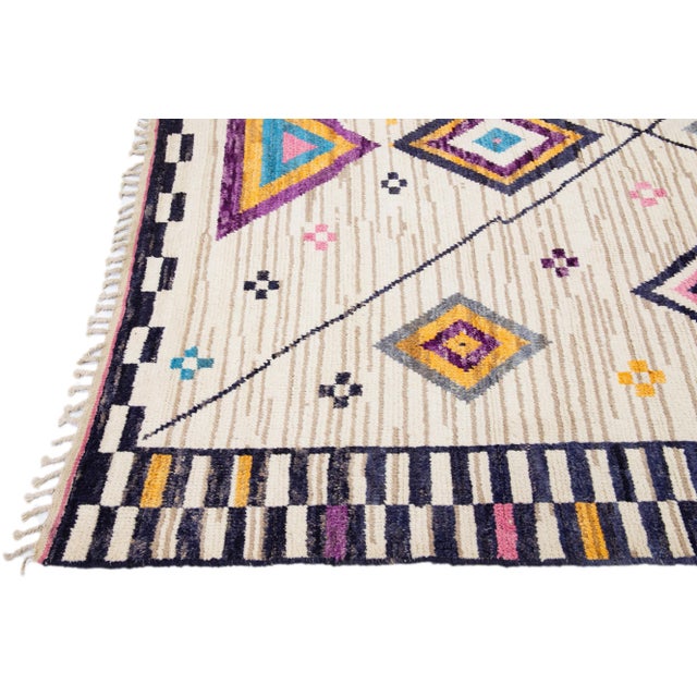 Beautiful modern Moroccan-style hand-knotted wool rug with a beige field. This piece has multicolor accent colors in a...