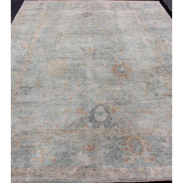 Turkish Oushak rug with seafoam green, light blue, tan, orange neutral color palette and all-over flower design. Keivan...