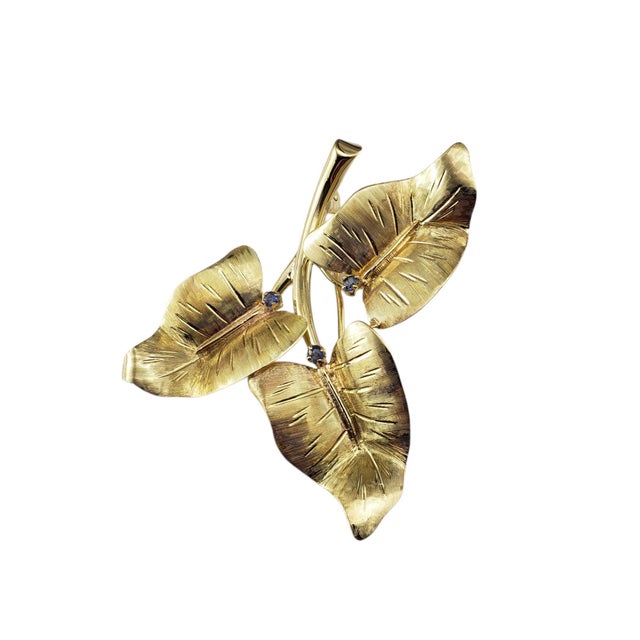 Tiffany & Co. 18 Karat Yellow Gold and Sapphire Leaf Brooch/Pin This exquisite brooch by Tiffany & Co. features a...