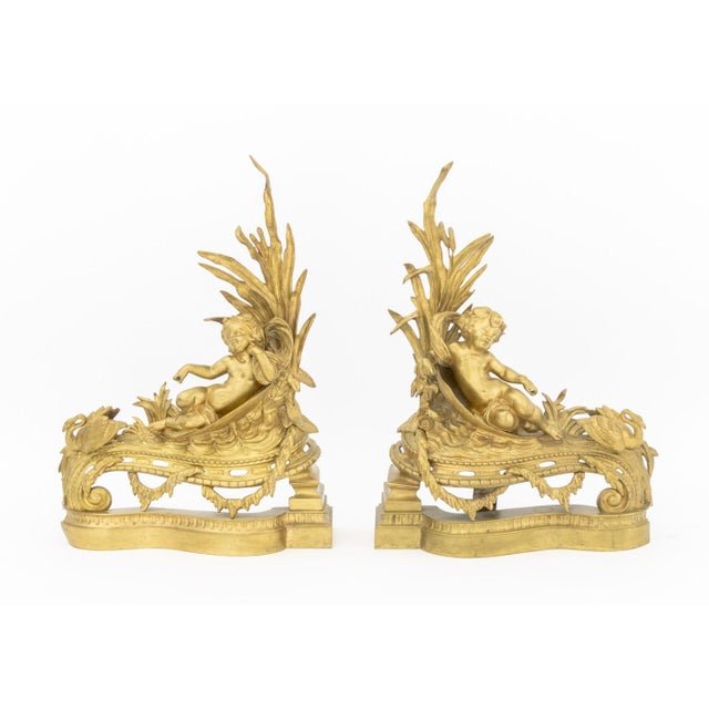 Pair of Louis XV Style Cupid Motif Brass Chenets, late 19th century, cherub reclining under cattails alongside swan. 21.5"...