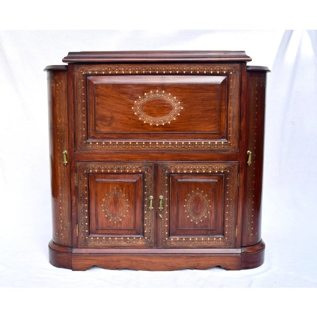 Midcentury bar cabinet of radiant grain solid Rosewood with intricate brass inlay details throughout. Substantial mirrored...