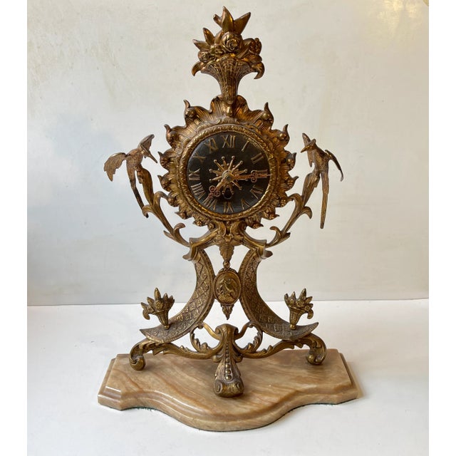 Ornate mantel clock in ormolu gilt brass upon a marble base. Extensive details: guarding eagles, center code of arms,...
