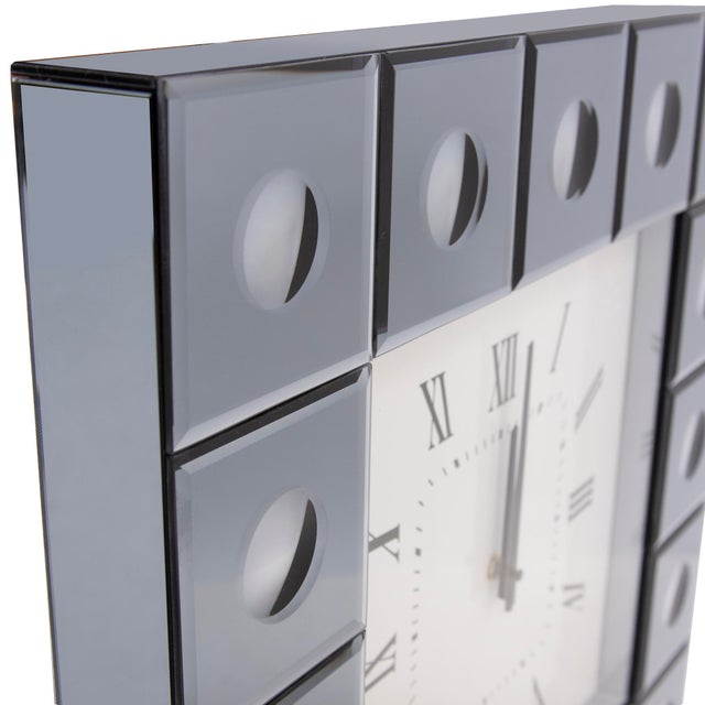 The Grigio Mirrored Clock features a square frame composed of smoked gray mirrored tiles. At the center of each tile is a...