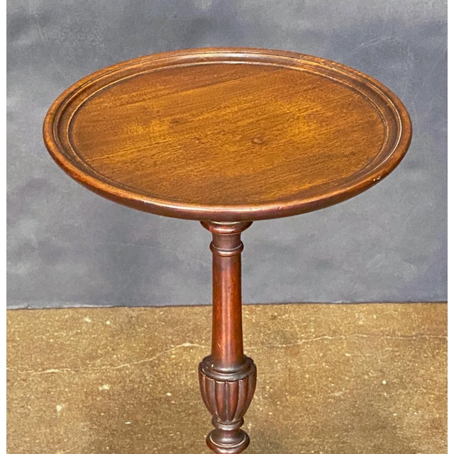 A fine English wine or cocktail table of mahogany from the Edwardian era, featuring a raised edge around the circumference...