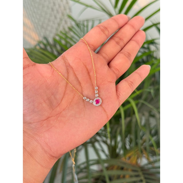 This pendant necklace features a 0.46 carat oval-cut red ruby and diamond, set in 14K yellow gold. The ruby measures...