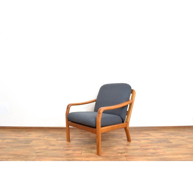 This teak armchair produced in Denmark in the 1970s by Dyrlund. The armchair frame is made of solid teak which has been...