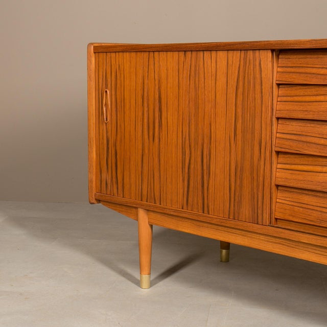 Discover the exceptional craftsmanship of this unique teak sideboard by Nils Jonsson, boasting a distinctive Scandinavian...