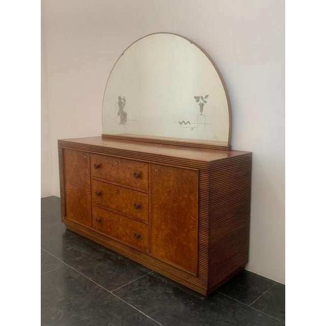 Decorated crescent mirror depicting ladies that is mirrored and flower vase. structure a grissined base wrigh walle 1940