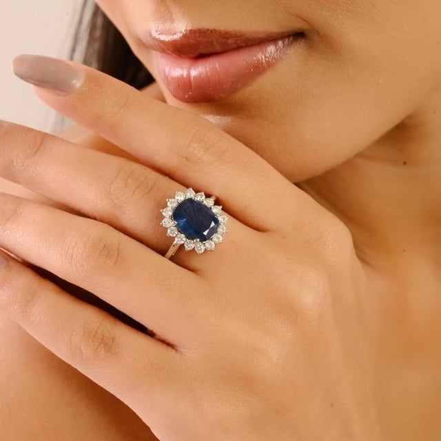 This exquisite cocktail ring features a cushion-cut deep blue natural sapphire at the center, measuring approximately 10 x...