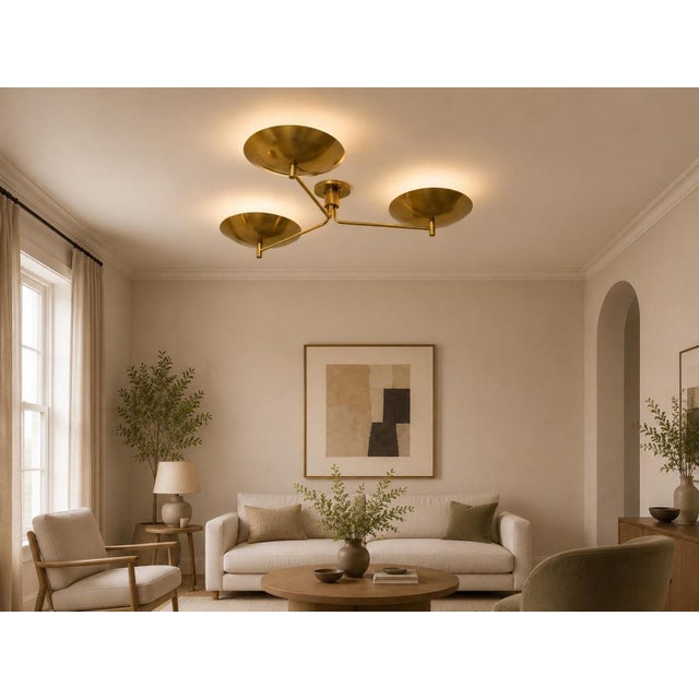 A handcrafted solid brass three-light flush mount ceiling fixture featuring sculptural bowl shades and a refined...