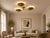 A handcrafted solid brass three-light flush mount ceiling fixture featuring sculptural bowl shades and a refined...