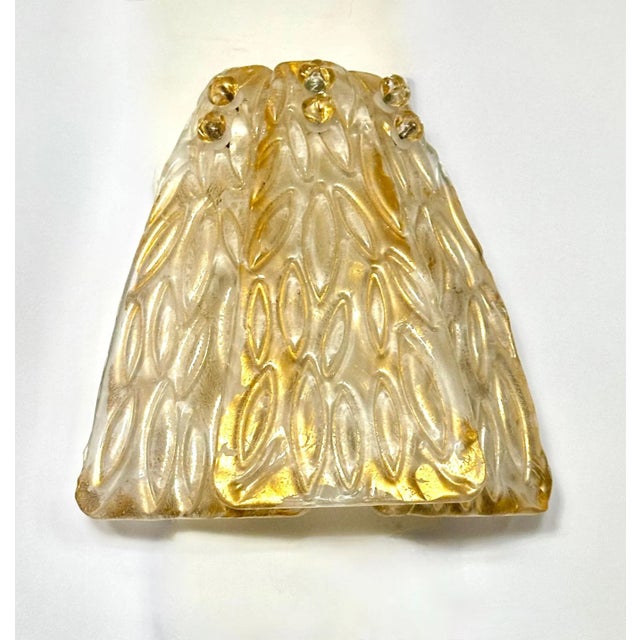 One single hand blown clear and gold surface inclusions glass leaf shaped wall sconce, supported on white metal backplate....