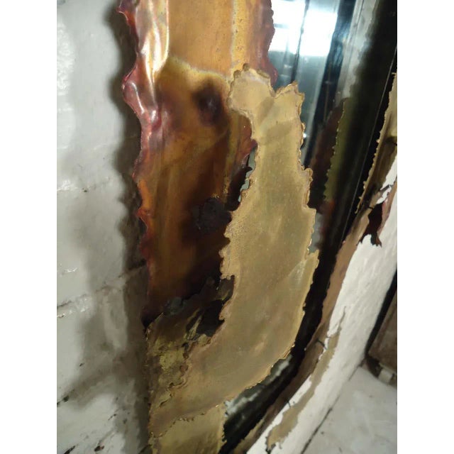 Striking brutalist style mirror made with torch cut sheets of metal, and given a three dimensional design.