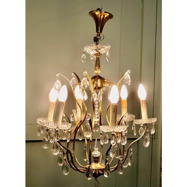 A Charming French Crystal and Brass Chandelier The elegant brass frame of this light forms a cage shape with the branches...