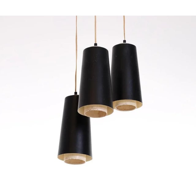 Three-armed pendant produced by Luco, Sweden, 1950s. Lacquered aluminum and steel with a brass ceiling mount. This piece...