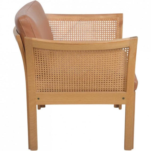 Illum Wikkelsø Plexus lounge chair, model 1, with a frame of oak and cushions upholstered in cognac leather. The chair is...