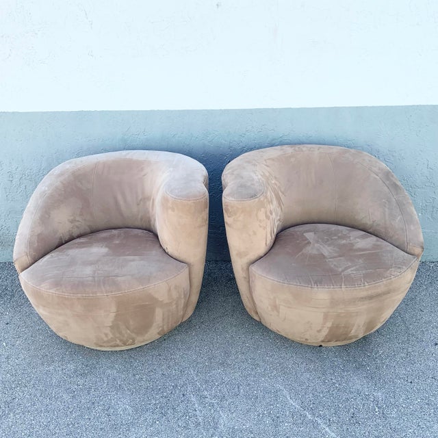 A sculptural pair of postmodern swivel lounge chairs, defined by their distinctive nautilus-inspired silhouette and softly...