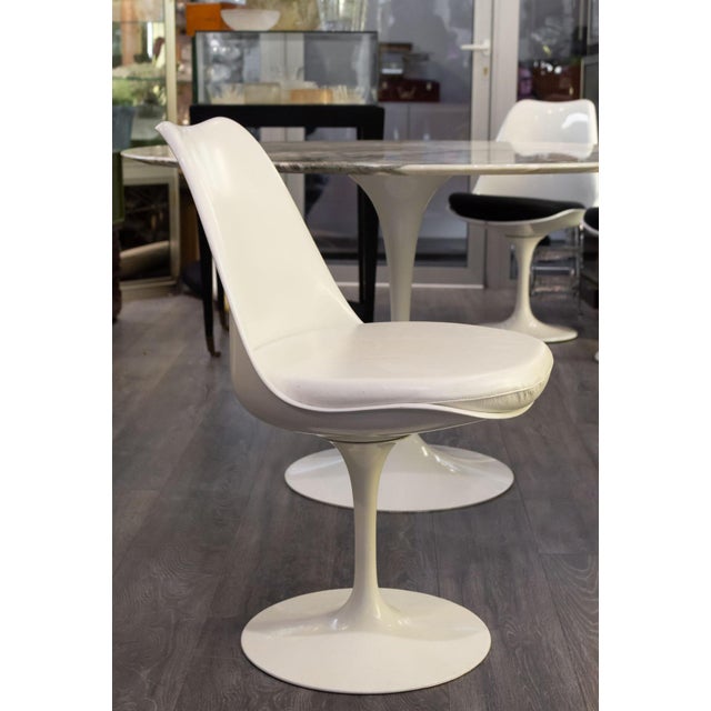 Swivel "Tulip" chair with a white fiberglass shell on a white lacquered cast aluminum base. Removable white vinyl cushion....