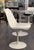 Swivel "Tulip" chair with a white fiberglass shell on a white lacquered cast aluminum base. Removable white vinyl cushion....