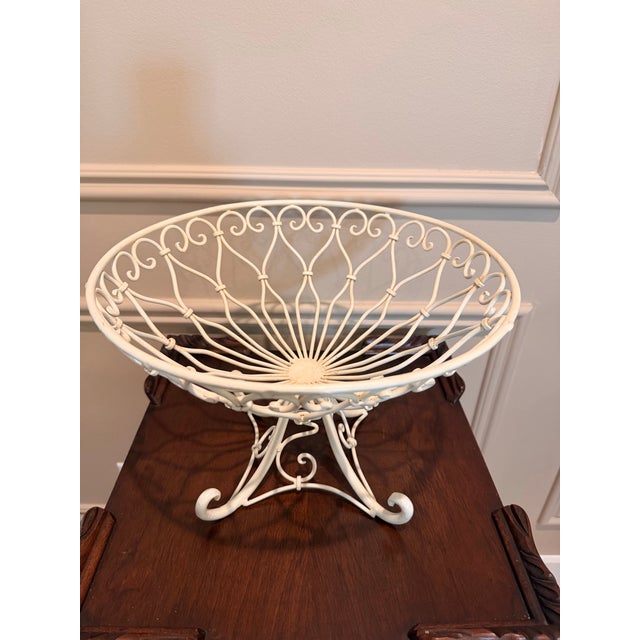 Decorative vintage heavy wirework pedestal basket in painted cream/white metal with elegant scrolling details and tripod...