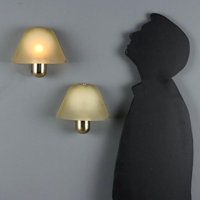 Two wall lamps crafted from brass and Murano glass, VeArt manufacture from the 1980s. The brass structure adds a touch of...