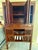 A large two-part wooden storage cabinet featuring four upper panel doors with intricately carved openwork fretwork...