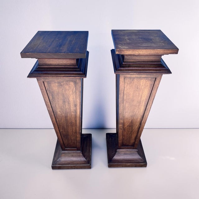 An elegant pair of vintage Italian handcrafted wood display pedestals featuring a rich walnut finish, architectural...