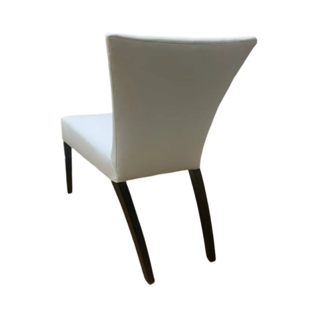 This is the Sevilla Chair by Brueton. It is upholstered in a cream fabric with dark maple legs.