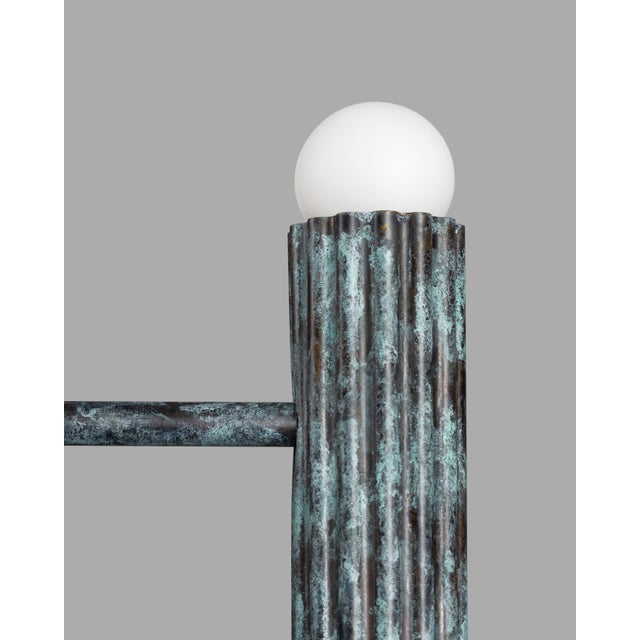Twelve vertical fluted cylinders from solid brass adorned with bulbs at both extremities, capturing rhythm and structure....