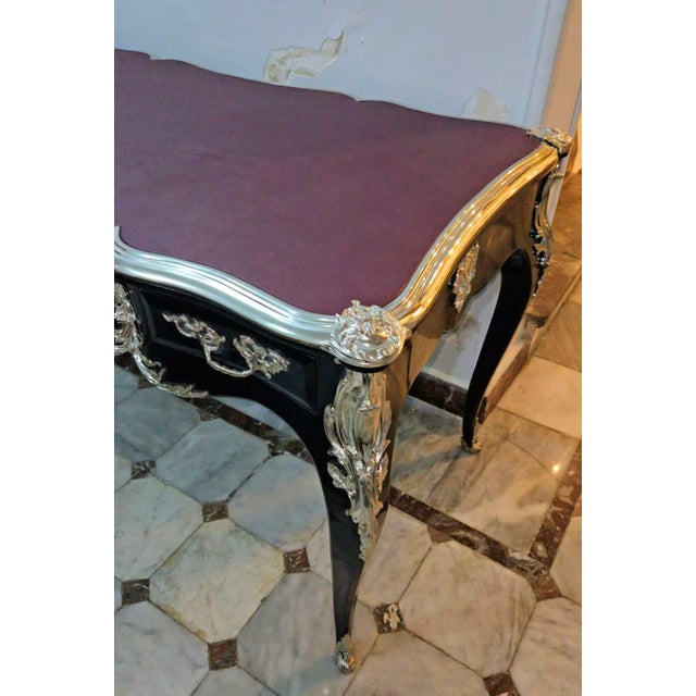 This elegant French Louis XV style writing desk features a luxurious burgundy leather writing surface beautifully...