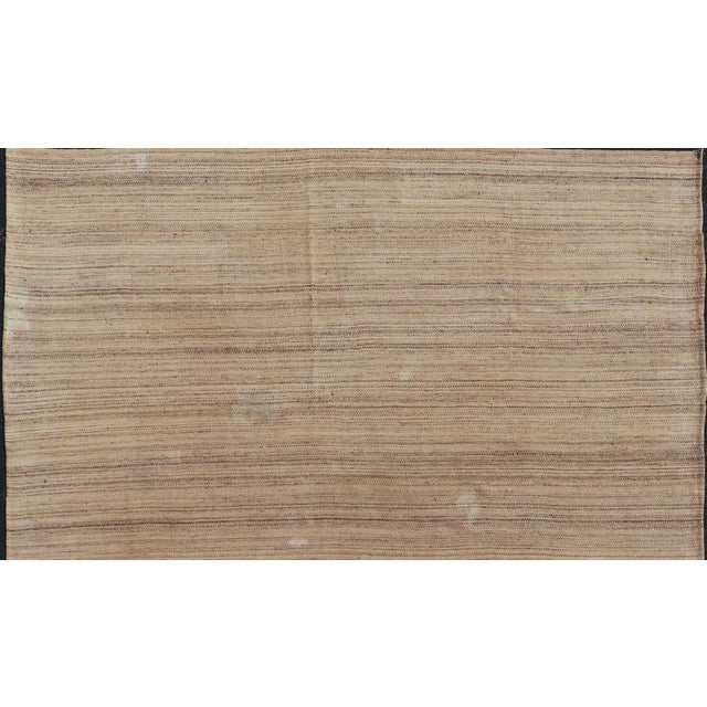 This flat-weave tribal Turkish kilim has been hand-woven in wool. The rug features an all-over striped design, and is...
