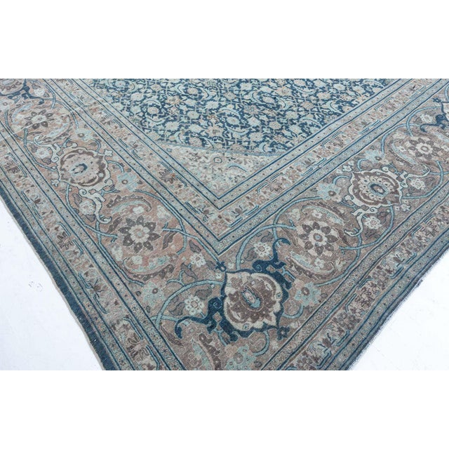 This circa 1920 antique Tabriz Persian rug features a rich dark blue field covered with an allover lattice of dense...