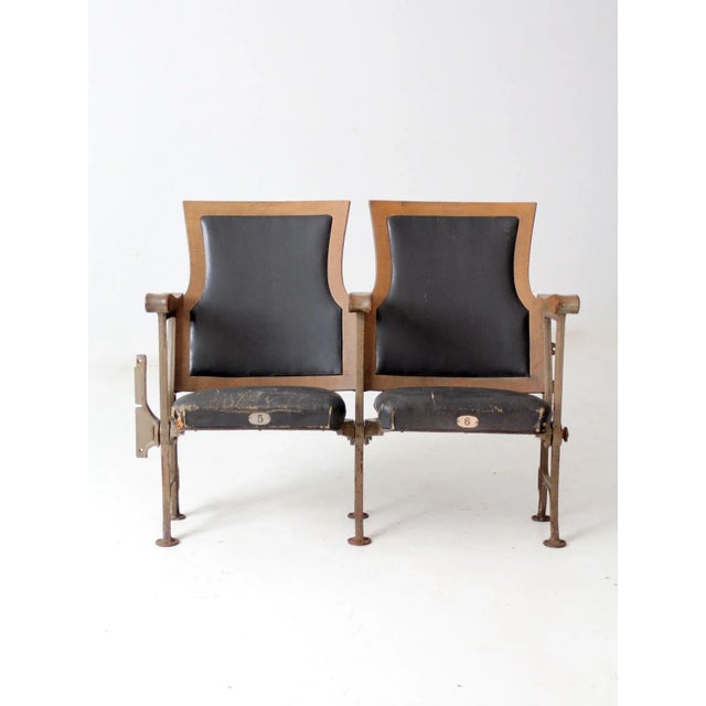 Here are a pair of antique American theatre seats circa early 20th century. The cast iron and wooden bench chairs feature...