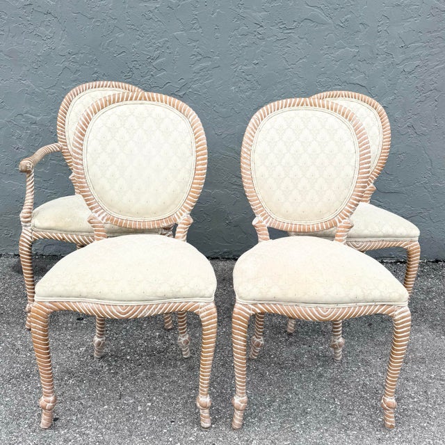 A charming set of four vintage French Provincial dining chairs, featuring three side chairs and one captain’s chair with...
