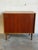 This compact storage piece features a clean rectilinear form with smooth sliding doors revealing interior shelving. Its...