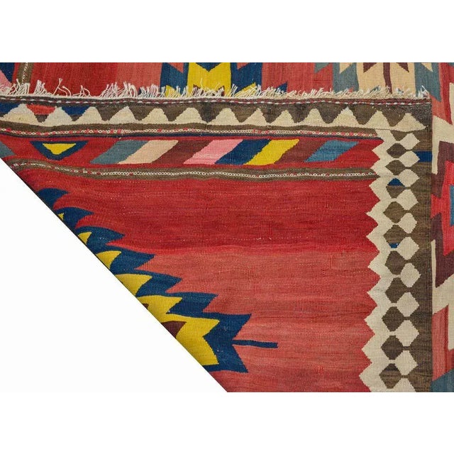 A wonderful early 20th century Persian Kilim runner with a bold pattern containing eight large stylized floral medallions...