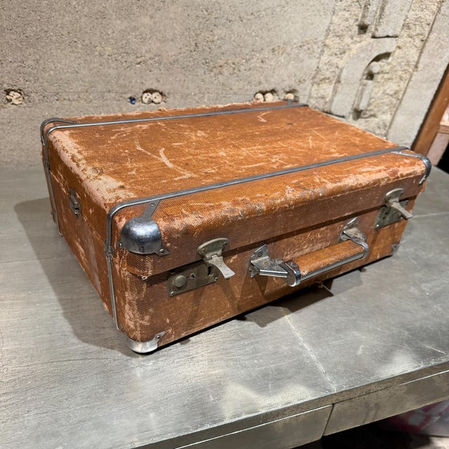 For your consideration, a weathered brown vintage suitcase with metallic latches and corner reinforcements.These types of...