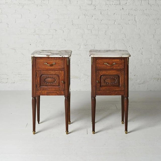 This pair of circa 1920s Belgian Louis XVI style bedside tables blends refined neoclassical elegance with timeless...